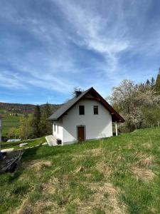 uma pequena casa branca no topo de uma colina relvada em Domek na Skarpie em Wisla