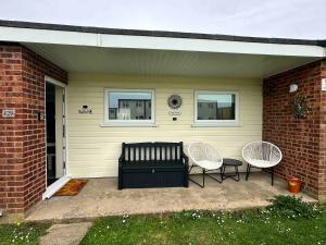 a patio with two chairs and a couch and two windows at 129 Sunset Chalet in Hemsby