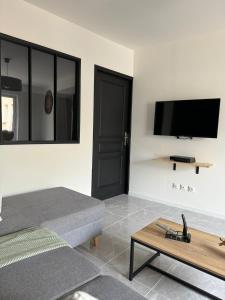 een woonkamer met een bank en een flatscreen-tv bij La maison de LYA (lyaroom) 