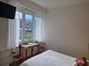 a bedroom with a bed and a desk and a window at Hotel Bellevue in Chambon-sur-Lac