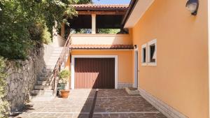 ein orangefarbenes Haus mit Garage und Treppe in der Unterkunft Apartment Pergola in Veprinac