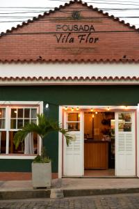 a pizza shop with a palm tree in front of it at Pousada Vila Flor in Rio das Flores