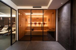 une porte en verre menant à une pièce avec sauna dans l'établissement Hotel Ladurner, à Merano