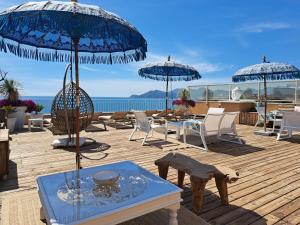 a deck with tables and chairs and umbrellas at Residence Veles Plage in Cannes