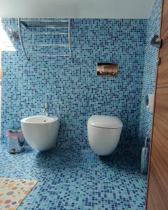 La salle de bains est pourvue de carrelage bleu, d'une baignoire et de toilettes. dans l'établissement Apartment Pergola, à Veprinac