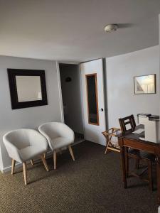 a living room with two white chairs and a desk at Auberge des Nuages in La Malbaie