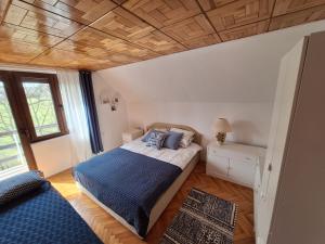 een slaapkamer met een bed en een houten plafond bij Planinska kuća Koreni in Jasikovice