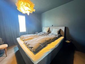 a bed in a blue room with a chandelier at Selbraut - Birta Rentals in Reykjavík