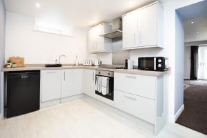 una cocina blanca con armarios blancos y un aparato negro en Garden Apartment - Close to Town Centre - sleeps 6 en Buxton