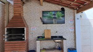 uma pequena cozinha com uma televisão na parede em Casa ampla e agradável com piscina e churrasqueira em Juazeiro