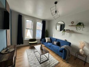 uma sala de estar com um sofá azul e uma mesa em Stylish Appt in Medway ideal for NHS and contractors, free parking em Gillingham