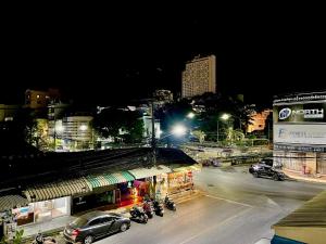 una calle de la ciudad por la noche con coches y motocicletas en Lamoon 90s en Hat Yai