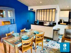 una cucina con tavolo, sedie e parete blu di IDR-0023 - Maison au cœur du village a Saint-Clément-des-Baleines