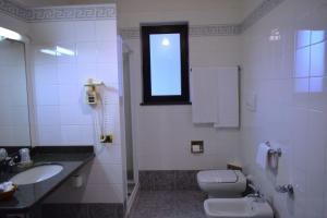a bathroom with a toilet and a sink and a window at Hotel 90 in Capurso