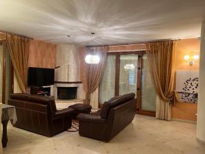 sala de estar con 2 sillas de cuero y TV en CASA SARADO en Polignano a Mare