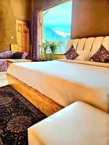 a bedroom with two beds and a large window at Hotel Old Manali - The Best Riverside Boutique Stay with Balcony and Mountain Views in Manāli