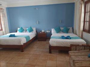 a blue room with two beds and a couch at Blue Planet Lodge & Restaurant in Pokhara