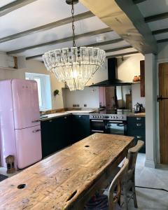 una cucina con tavolo in legno e frigorifero rosa di The Old Forge a Cheltenham