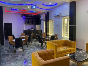 a living room with couches and tables and a piano at Diamond Castle Hotel in Owerri