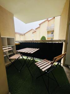 2 mesas de picnic y sillas en el balcón en Appartement Cosy et Confortable en Saint-Genis-Laval