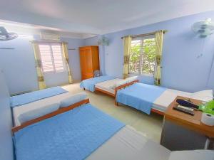 a bedroom with two beds and a desk and two windows at Nhà Nghỉ Kiên Cường - Kien Cuong Hostel in Cat Ba