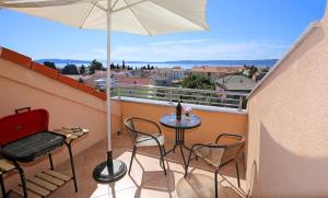 einen Balkon mit einem Tisch, Stühlen und einem Sonnenschirm in der Unterkunft Top apartment in Kaštela