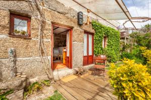 a stone house with a wooden porch with a door at Casa da Benfeitoria in Guimarães