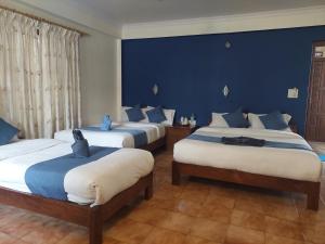 a bedroom with three beds with blue walls at Blue Planet Lodge & Restaurant in Pokhara