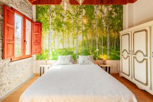 a bedroom with a large bed with a mural of trees at Casa da Benfeitoria in Guimarães