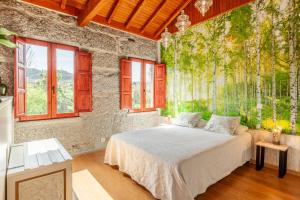 a bedroom with a bed and trees on the wall at Casa da Benfeitoria in Guimarães