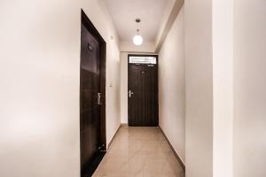 korytarz z czarnymi drzwiami i podłogą wyłożoną kafelkami w obiekcie Super OYO AARAV HOTEL w mieście Dżajpur