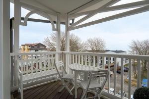 una veranda bianca con 2 sedie e un tavolo di Haus-Ostseeapartments-am-Fehmarnsund-Wohnung-27-Strandrubin a Grossenbrode