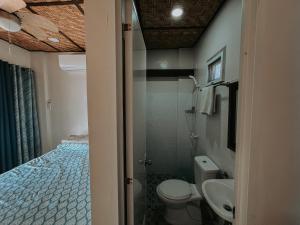 a bathroom with a bed and a toilet and a sink at Gloria's Beach House in Oslob