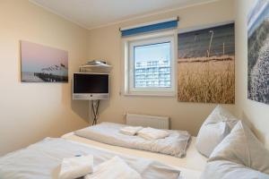 una camera da letto con due letti e una TV a parete di Haus-Ostseeapartments-am-Fehmarnsund-Wohnung-27-Strandrubin a Grossenbrode