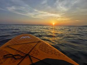 a kayak in the water with the sunset in the background at Apartments Riva Povljana in Povljana