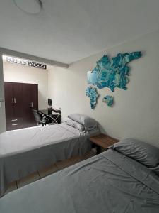 a bedroom with two beds and a desk with a laptop at Casa Petfriendly Bosque de la Primavera in Guadalajara