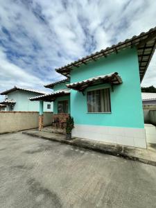 a green house with a blue at Casa Maresia in Saquarema