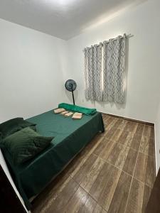a bedroom with a green bed and a window at Casa Maresia in Saquarema