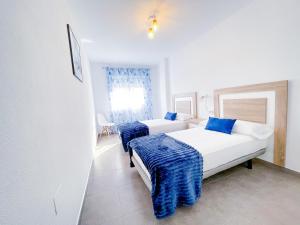 2 camas en una habitación blanca con mantas azules en Modern Three bed Apartment, en San Pedro del Pinatar