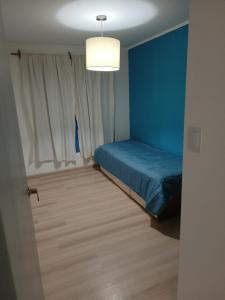 Dormitorio azul con cama y ventana en Casa Catalina zona sur en Comodoro Rivadavia
