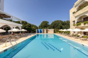 a large swimming pool with chairs and umbrellas at Stephanos Hotel Apartments in Polis Chrysochous