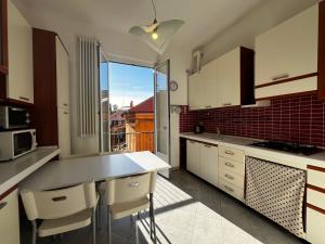 une cuisine avec des placards blancs et une grande fenêtre dans l'établissement Sant'Andrea Appartamento nel borgo antico, à Levanto