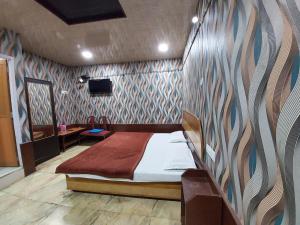 1 dormitorio con 1 cama y TV en la pared en Hotel Neelam Raj Nainital Near Mall Road - Excellent Service Awarded - Near Lake, en Nainital