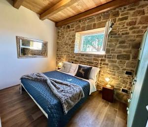 1 dormitorio con 1 cama con pared de piedra en Villa Lux en Poppi