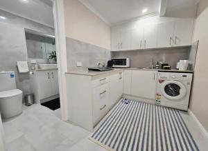 a white kitchen with a washer and a sink at Cosy Unit at Modbury in Modbury