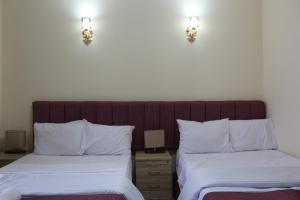 a bedroom with two beds and two lights on the wall at pyramita luxury hotel in ‘Ezbet `Abd el-Ḥamîd