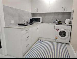 a white kitchen with a washing machine and a washer at Cosy Unit at Modbury in Modbury