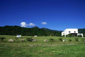a white house in a field with mountains in the background at The Blue Lagoon B&B in Fengbin