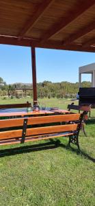 a wooden bench sitting under a roof in a field at Cabaña El Cardenal in Tandil