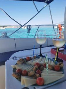 un vassoio di cibo su una barca con due bicchieri di vino di Apartments Lucia a Pag